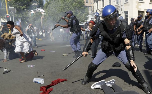FILE - Students run for cover as police fire stun grenades and rubber bullets in an attempt to disperse them, during their protest for free education in Johannesburg, South Africa, Sept. 21, 2016.