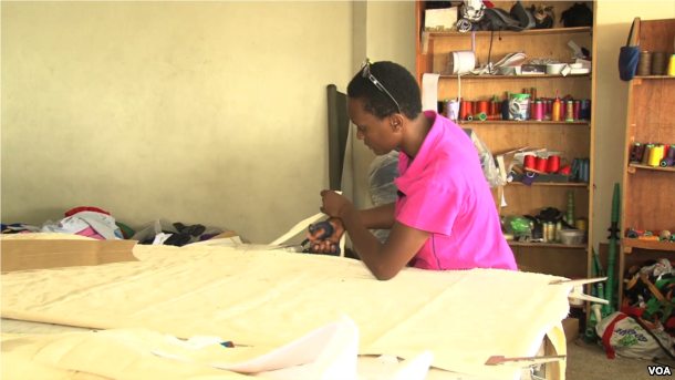 Lilian Wairimu cuts the material needed for the beanbag. The material is cut into eight pieces with inner and outer lining, then is stitched together with a zipper to hold the foam perfectly. (M. Yusuf/VOA)