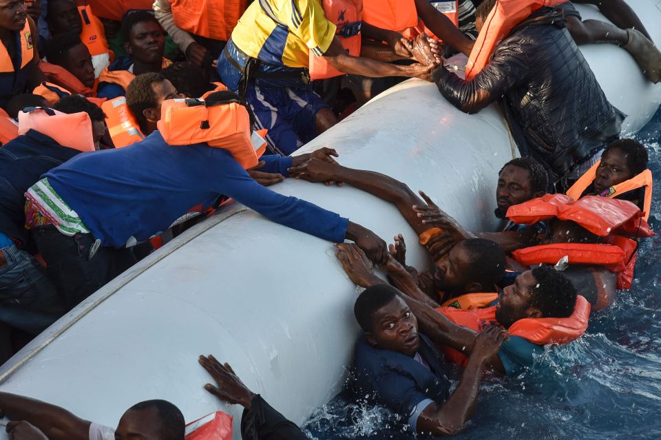 Desperate migrants cling onto the side of a boat during their rescue, while two other migrant ships sank killing around 240 people